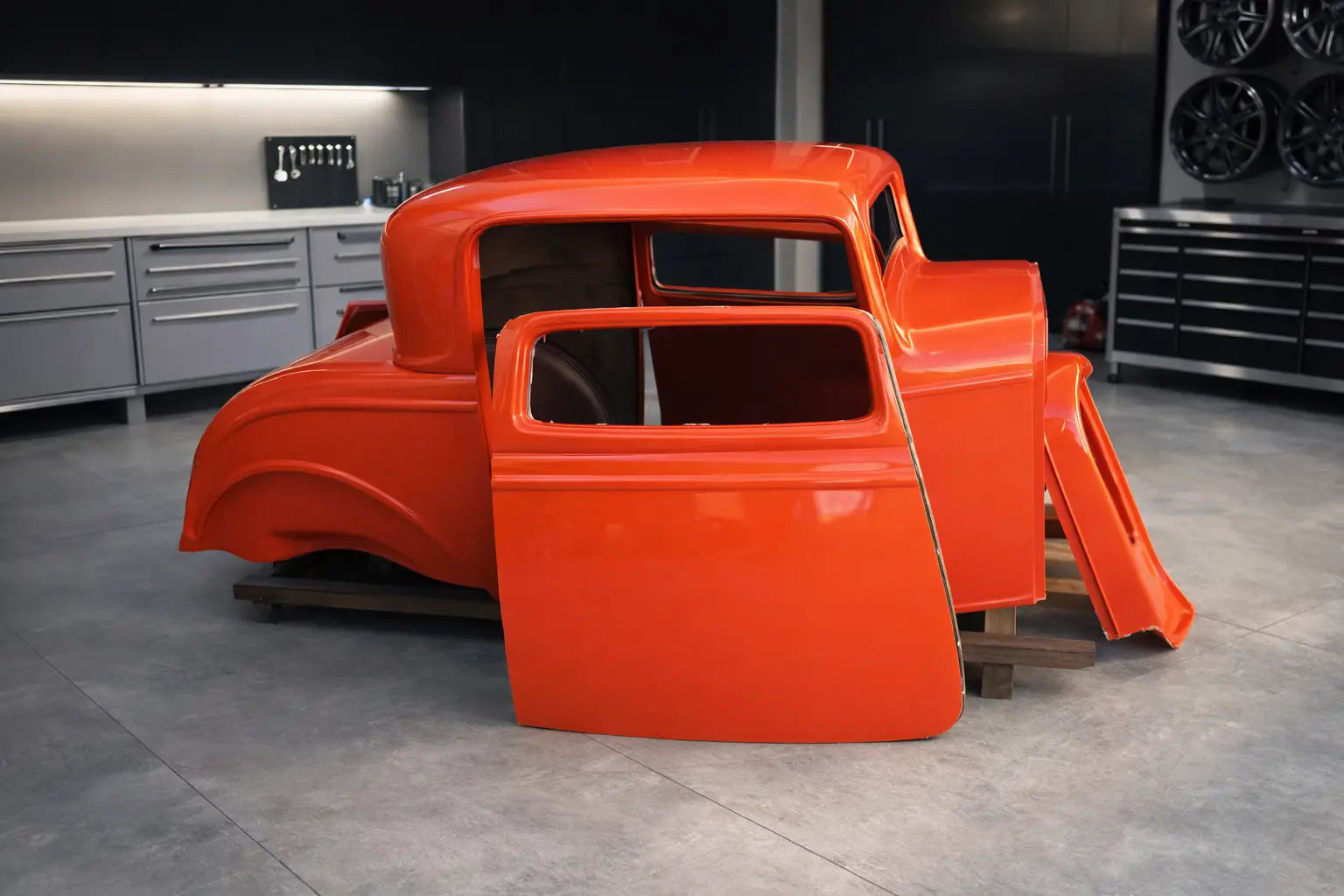 Orange vintage car body on a stand in a workshop setting after fibreglass repair